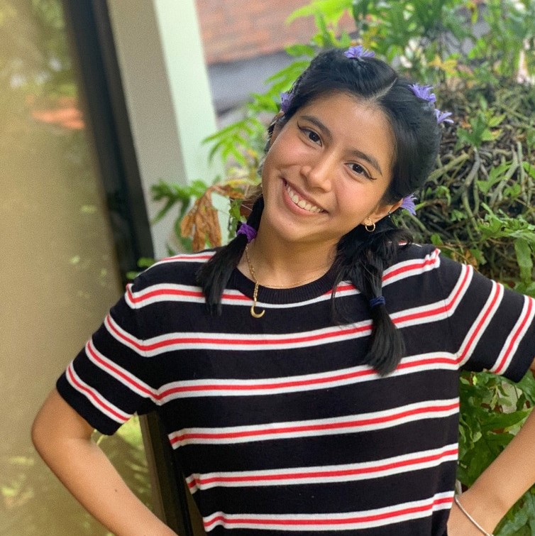la imagen puede contener a uan mujer peinda con dos trenzas,de pie posando sonriente.